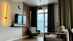 a living room with a tv and a chair and a window at Stylish apartments White Sails View in Batumi