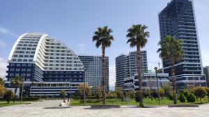 two tall buildings with palm trees in a park at Stylish apartments White Sails View in Batumi