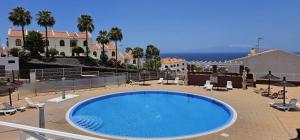 a large blue swimming pool on a patio with the ocean at Sunshine Beach Apartments in Adeje +20 photos