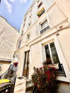a white building with flowers in a window at Nice studio with a terrace in Levallois-Perret