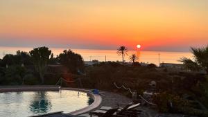 a sunset over a swimming pool in a resort at Dammuso Kazen Jezabel in Pantelleria +27 photos