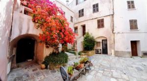 an alley with tables and flowers on a building at T1 au coeur de St Florent in Saint-Florent