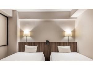 two beds in a room with two lamps on the wall at Sun Hotel Fukuyama - Vacation STAY 53489v in Fukuyama
