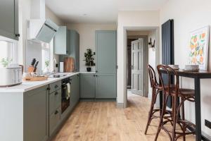 a kitchen with blue cabinets and a table and chairs at 1BR-3BR Apartments in Bangor, Mins to Seafront & High St in Bangor +17 photos