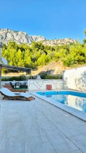 a house with a swimming pool next to a mountain at Studio Apartmani Šehić in Krvavica