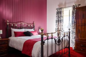 a bedroom with a bed with pink walls and a window at Lynrose Place in Stanthorpe