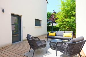 a patio with a couch and chairs and a table at Maison des Paradisiers - Welkeys in Le Crès