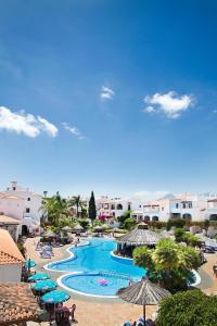 Una vista de la piscina de un complejo con sombrillas y sillas. en Fairways Club - TEIDE VIEW OASIS - heated pool, family apt, en San Miguel de Abona