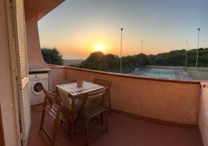 a table and chairs on a balcony with the sunset at Badesi Sunset View in Badesi