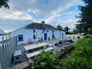 a white house with a picnic table and benches at The Olde Farmhouse 