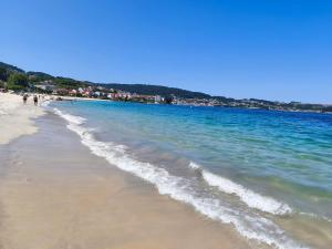 a beach with people walking on the sand and the water at Can do Penedo 8 in Bueu