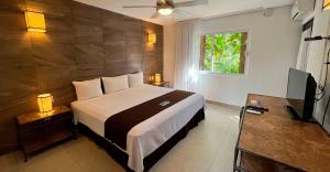 a bedroom with a bed and a television in it at Tukan Hotel Playa del Carmen in Playa del Carmen
