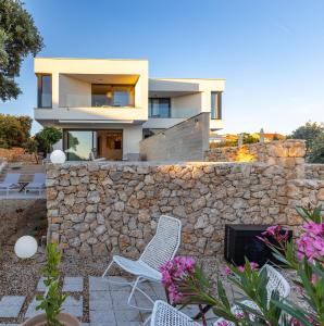 a house with a stone wall and two chairs at Vila Oliva i Terakota in Mandre