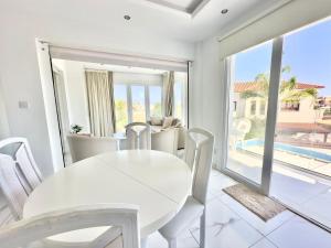 a white dining room with a white table and chairs at Lumière Retreat 2 in Larnaca