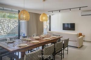 a dining room with a long table and chairs at Apto Moderno c/ piscina e 3 suítes - VKA0115 in Tatuamunha