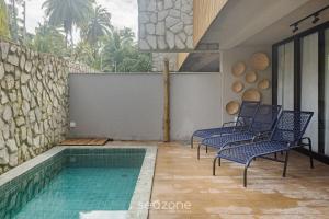 a patio with chairs and a swimming pool at Apto Moderno c/ piscina e 3 suítes - VKA0115 in Tatuamunha
