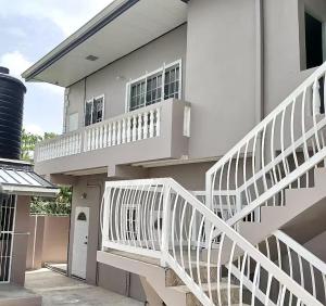 a white house with a white staircase in front of it at The Hibiscus Retreat in Arima