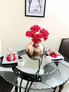 a glass table with a vase with red flowers on it at The Hibiscus Retreat in Arima