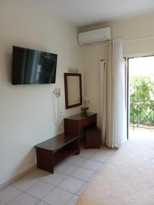 a living room with a tv on the wall and a mirror at Metaxa Apartments in Kavos