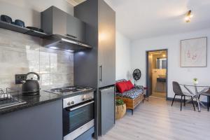 Cape Town Studio - Table Mountain Views, Gym, Free Parking, Free WiFi في كيب تاون: مطبخ مع موقد فرن علوي بجوار غرفة المعيشة