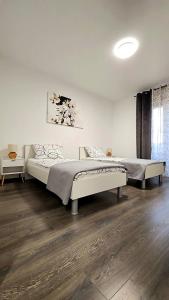 two beds in a bedroom with a wooden floor at Val Center in Novalja