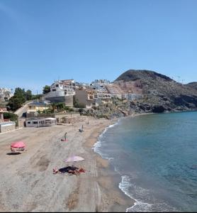a group of people laying on a beach with umbrellas at APARTAMENTO SOL - 2 apartamentos céntricos juntos cerca de la playa, ideales para grupos grandes in Águilas