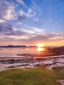a sunset over a body of water with the sun setting at Villa by the sea in Vesterålen 