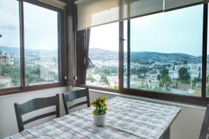 a table with a vase of flowers on a table with windows at Ayşem Mill Hill Houses in Bodrum City