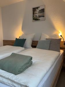 two beds with white sheets and green pillows at ZwoLu Apartments in Bornheim