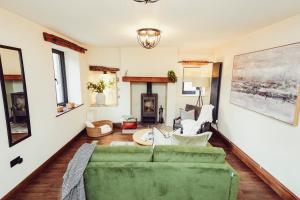 a living room with a green couch and a fireplace at Cottage near Matlock Bath & Cromford in Middleton
