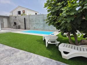 a yard with a pool and two chairs and a tree at Casitalola in Conil de la Frontera
