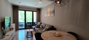 una sala de estar con un sofá y una mesa en Sea & Forest - Apartamenty Może nad Morze, Parking, basen, siłownia GRATIS, en Międzyzdroje