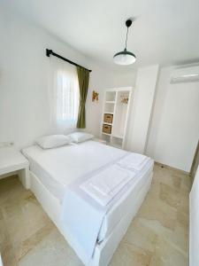a white bedroom with a white bed and a window at Çam Tatil Evleri in Datca +17 photos