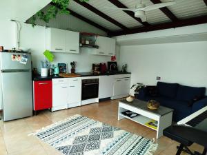 a kitchen with white cabinets and a blue couch at Petit cocon vue mer in Gourbeyre