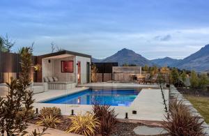 a house with a swimming pool with mountains in the background at Luxury Architectural Home with Pool, Spa and Sauna in Queenstown Airport