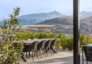 a table and chairs with mountains in the background at Luxury Architectural Home with Pool, Spa and Sauna in Queenstown Airport +55 photos