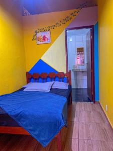 a bedroom with a bed with a blue and yellow wall at Chêles - Casa na Praia do taquari in Paraty