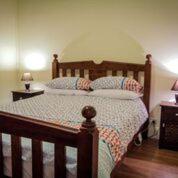 a bedroom with a wooden bed with two pillows at Heather's Mica Cottage in Broken Hill