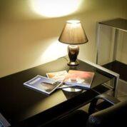 a desk with a lamp and a book on it at Heather's Mica Cottage in Broken Hill