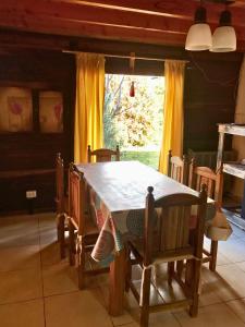 a dining room with a table and chairs and a window at Cabañas del Volga in El Hoyo
