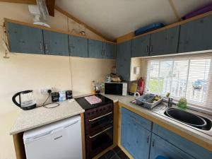 a small kitchen with blue cabinets and a sink at N&L Caravan Hire, The Highbury Caravan Park in Ingoldmells