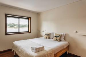 a bedroom with a large white bed with a window at Douro Riverfront 2BR with Private Terrace & Garage in Porto