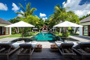 - une piscine avec des chaises et des parasols à côté d'une villa dans l'établissement Villa Tiga Puluh, à Seminyak
