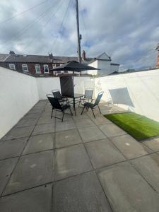 a patio with chairs and a table with an umbrella at Liverpool RD Warrington in Great Sankey