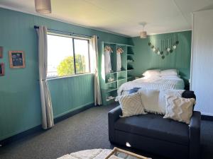 a bedroom with a bed and a couch and a window at Treetops in Blenheim