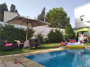 a backyard with a pool with an umbrella and a toy at Magnifique villa Olfa in Hammamet +2 photos