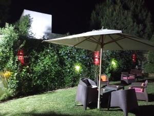 an umbrella and chairs on a lawn at night at Magnifique villa Olfa in Hammamet