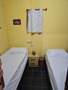 Dos camas en una habitación con una mesa y una toalla. en Hostel Yellow House MG, en Itamonte