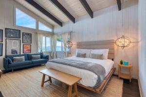 Un dormitorio con una cama grande y un sofá azul. en Lakeview by AvantStay Private Waterfront Cabin on Lake Tahoe w Hot Tub Views, en Tahoe Vista