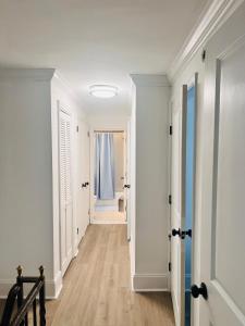 un corridoio con pareti bianche, pavimenti in legno e una porta di ComfiNook Cozy Suburb Stay Philly Airport Parking 